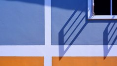 阳光和影子表面白色木窗口与蓝色的和橙色画墙装饰背景外体系结构概念