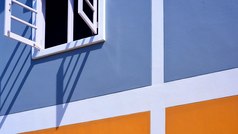 低角和一边视图白色木窗口蓝色的和橙色画墙装饰背景与阳光和影子表面外体系结构概念
