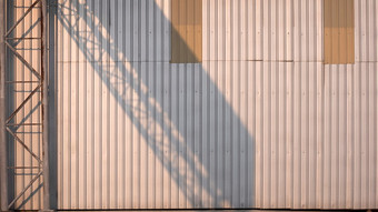 阳光和影子的老乡村金属开销路标结构金属表墙表面工厂建筑晚些时候下午时间工业和体系结构概念