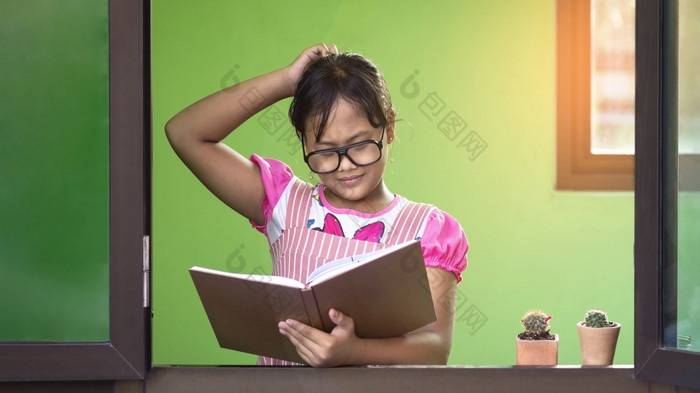 亚洲小黑暗剥了皮的女孩眼镜抓她的头怀疑和怀疑手势而阅读教科书玻璃窗口框架首页