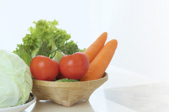 新鲜的西红柿胡萝卜和各种各样的绿色non-toxic蔬菜编织竹子篮子石头大理石表格白色背景健康的食物概念