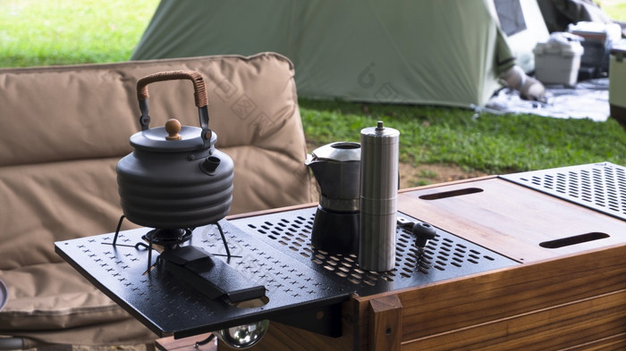 古董户外黑色的水壶和咖啡磨床野营表格与扶手椅绿色草坪上野营区域