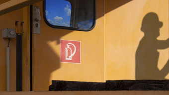 一边视图红色的火灭火器标志火车头通过与阳光和影子工程师表面橙色火车墙在的检查和维护车库