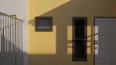 白色木通过和存储室与阳光和影子黄色的房子建筑墙