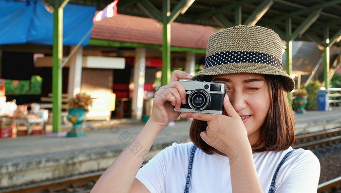 年轻的漂亮的亚洲女旅行者休闲风格与他采取照片与古董相机铁路平台火车站生活方式旅行概念