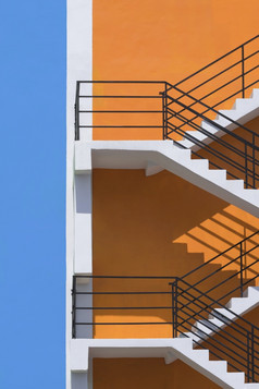 阳光和影子表面火逃避外橙色和蓝色的建筑墙垂直框架