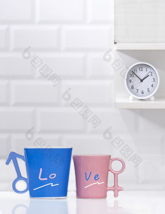 夫妇蓝色的和粉红色的咖啡杯子与轮表格时钟架子上白色瓷砖墙背景