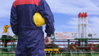 后视图和上腹部工程师持有黄色的安全头盔与模糊背景原油石油油轮船厂区域