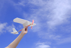 孩子手持有橡胶动力飞机的空气对蓝色的天空背景