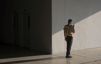 亚洲安全警卫安全背心使用步话机而工作人行道上地下停车车库
