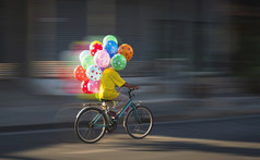 运动模糊亚洲气球卖方骑自行车的街晚上时间