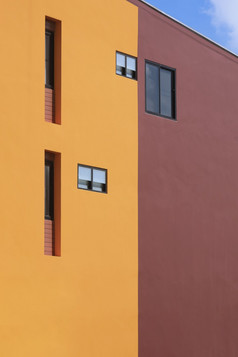背景各种各样的修复玻璃窗户橙色和棕色（的）现代建筑墙与蓝色的天空的角度来看一边视图和垂直框架