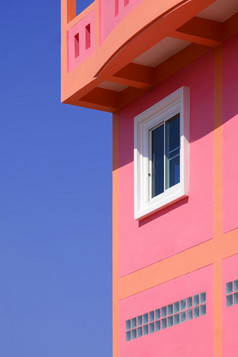 阳光白色玻璃窗口表面古董色彩斑斓的粉红色的建筑对蓝色的清晰的天空垂直框架