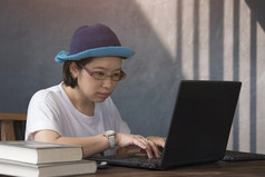 亚洲休闲女人使用移动PC电脑木桌子上而工作从首页古董生活房间