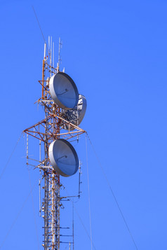 沟通电信塔与雷达和天线对蓝色的清晰的天空垂直框架
