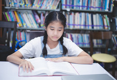 亚洲女孩学生阅读书和使用笔记本的图书馆