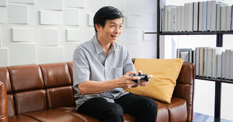 高级亚洲男人。使用平板电脑和虚拟现实模拟器玩游戏生活房间和感觉快乐生活方式高级家庭首页概念