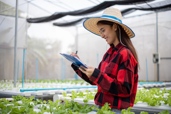 亚洲女人<strong>农民</strong>使用平板电脑和笔记本为检查的质量有机<strong>蔬菜种植</strong>使用水培法