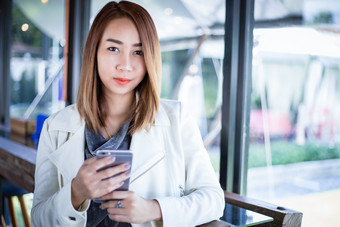 女人亚洲使用电话为购物在线和调用与细胞电话咖啡商店在免费的时间