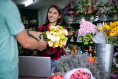 亚洲女人花店小业务花商店老板和她使用她的电话和移动PC取订单为她的商店