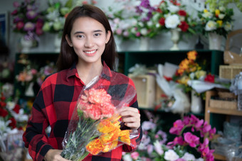 微笑女人花店小业务花商店老板和年轻的花店检查花的商店