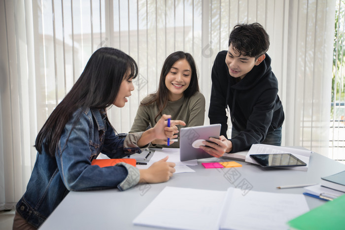 集团亚洲学生微笑和阅读书和使用笔记本为帮助分享的想法的工作和项目和也审查的书之前的考试