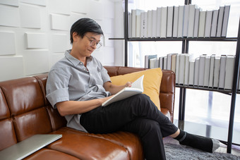 高级亚洲男人。阅读书沙发生活房间首页肖像亚洲上了年纪的男人。放松和幸福与读杂志