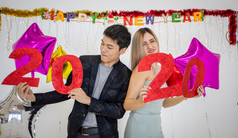 亚洲夫妇情人持有数字庆祝新一年酒吧大喊大叫和笑和计数下来午夜新一年聚会，派对