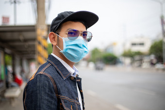 亚洲年轻的男人。站的城市和穿保护面具脸为保护空气污染微粒和为保护流感病毒流感冠状病毒城市