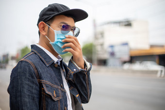 亚洲年轻的男人。站的城市和穿保护面具脸为保护空气污染微粒和为保护流感病毒流感冠状病毒城市