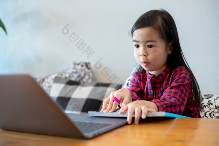 亚洲女孩女儿使用笔记本电脑和技术为在线学习在学校假期和看漫画首页教育概念和活动的家庭