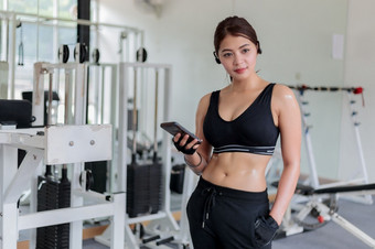 亚洲运动员运动服装时尚服装女运动员听音乐使用电话应用程序为健身活动跟踪器心率监控跟踪她的健康进步智能手机