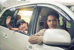 快乐小女孩与亚洲家庭坐着的车为享受路旅行和夏天假期