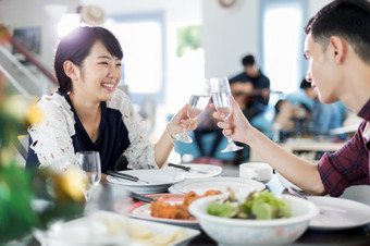 亚洲年轻的夫妇享受浪漫的<strong>晚餐</strong>晚上饮料而坐着的餐厅表格的厨房在一起