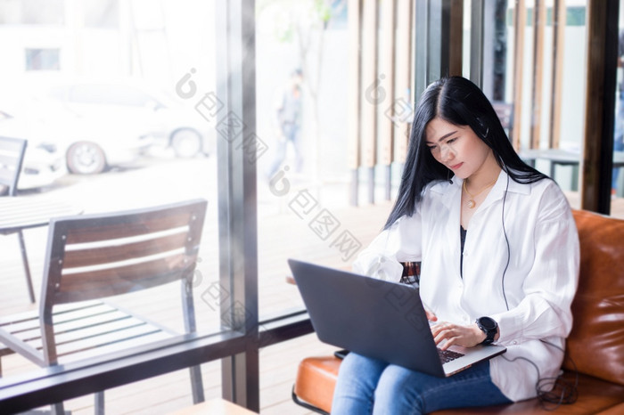 亚洲女商人是使用笔记本电脑和穿耳机为在线会议和工作从首页
