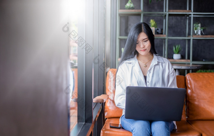 亚洲女商人是使用笔记本电脑为工作从首页她微笑快乐和享受工作