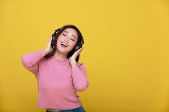 快乐快乐的<strong>美丽</strong>的亚洲女人穿无线耳机享受听音乐黄色的背景<strong>人生</strong>活方式概念