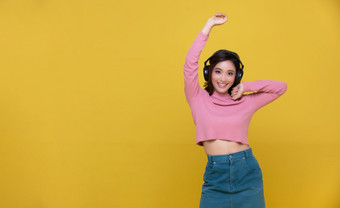 快乐快乐的美丽的亚洲女人穿无线耳机享受听音乐黄色的背景人生活方式概念