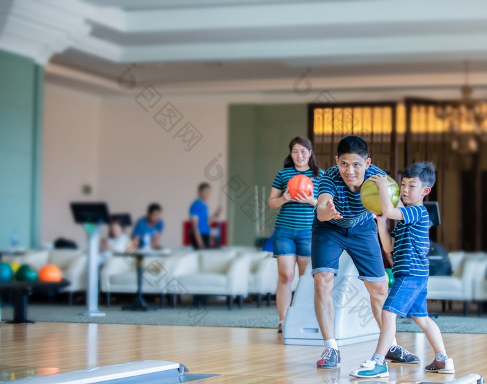 父亲教学儿子和家庭玩打保龄球打保龄球俱乐部放松时间家庭活动假期概念