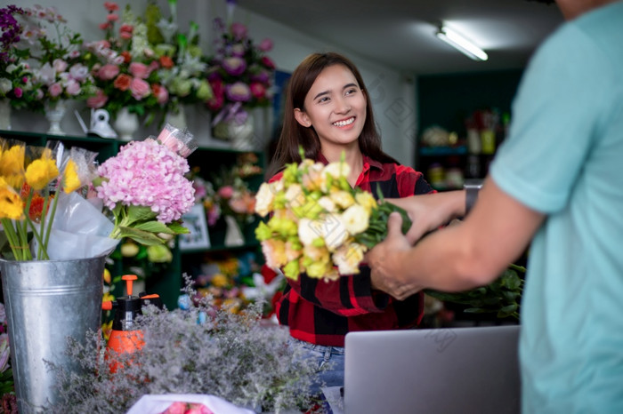 亚洲女人花店老板小花店业务持有花为交付客户她的商店