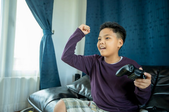 亚洲男孩享受玩视频游戏在一起与视频操纵杆与激发和非常有趣的的生活房间首页