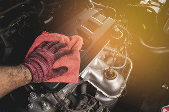 手清洁引擎封面与使用红色的超细纤维布汽车维护概念