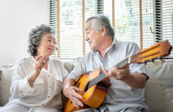 浪漫的亚洲高级夫妇唱歌和玩声吉他在一起快乐微笑上了年纪的吉他手男人。和老歌手女人有有趣的和享受他们的退休生活生活方式仪器聚会，派对