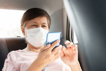 亚洲<strong>高级</strong>女人乘客穿外科手术面具为防止冠状病毒新冠病毒使用智能手机而坐着车流<strong>感</strong>大流行病毒公共运输