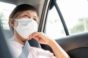 亚洲高级女人乘客穿外科手术面具为防止和保护冠状病毒新冠病毒而坐着车公共运输环境卫生健康的流感大流行病毒
