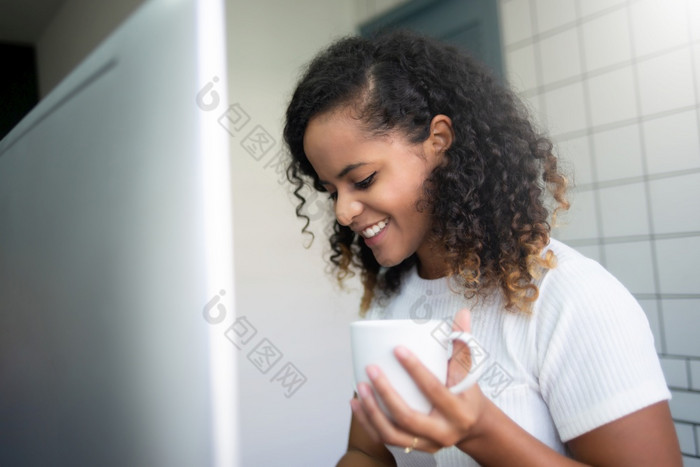 有吸引力的拉美裔女人白色衬衫微笑和使用移动PC电脑而坐着首页年轻的美丽的女混合比赛自由职业者与卷曲的头发放松而在线工作