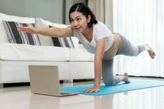 健身美丽的亚洲怀孕了女人练习瑜伽与在线类移动PC首页健康的年轻的女伸展运动在锻炼而她的怀孕锻炼健康和健康哪