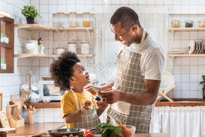 非洲美国父亲和小儿子玩和笑在烹饪厨房黑色的家庭有有趣的准备健康的食物在一起首页巴西单爸爸和男孩与微笑脸