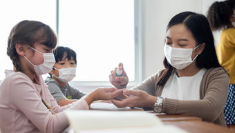 学生与保护脸面具清洁手与洗手液可移植的过来这里而病毒流感大流行学校老师女喷涂酒精喷雾学生手掌为防止冠状病毒教室