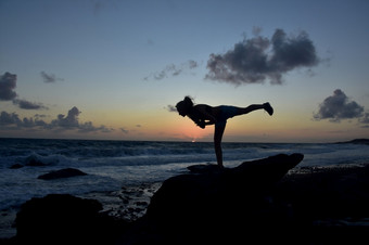 战士瑜伽平衡构成与太阳不断上升的在的海洋